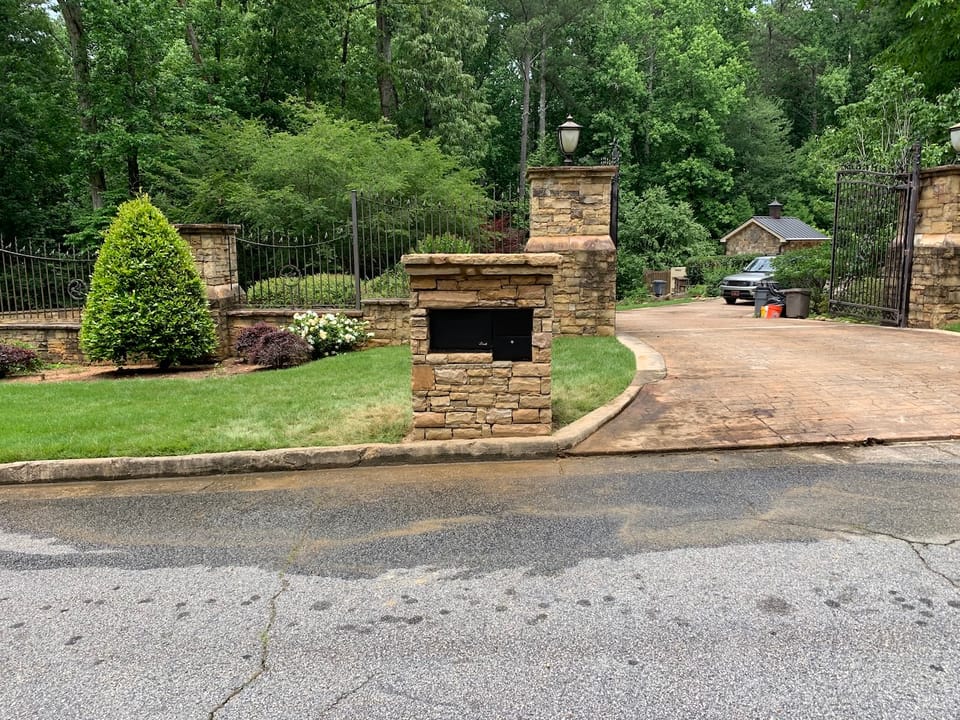 Stone mailbox with a package vault at a gated estate driveway in Tucker